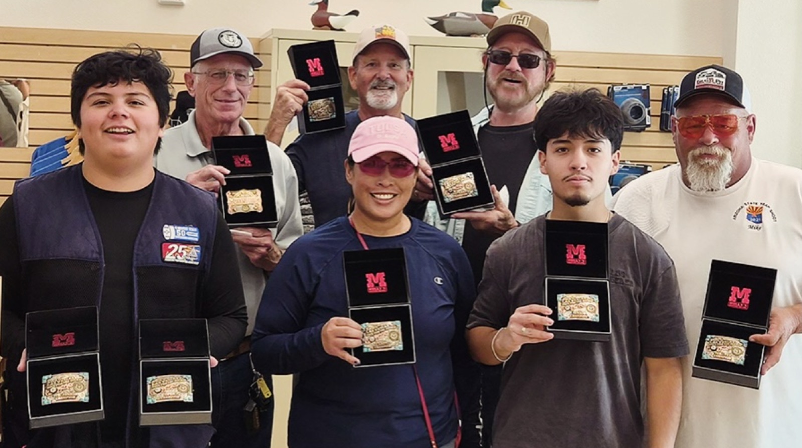 Eight 2025 Las Vegas Big 50 buckle winners holding their belt buckles